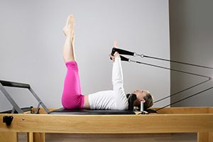 Idris is instructing a female client on a Pilates move on the reformer